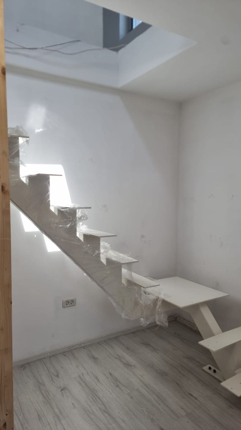 Scară interioară albă pe grindă centrală, cu trepte în consolă