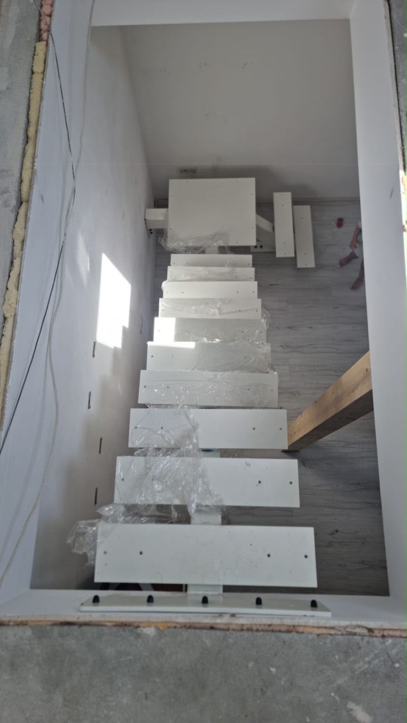Scară interioară albă pe grindă centrală, cu trepte în consolă